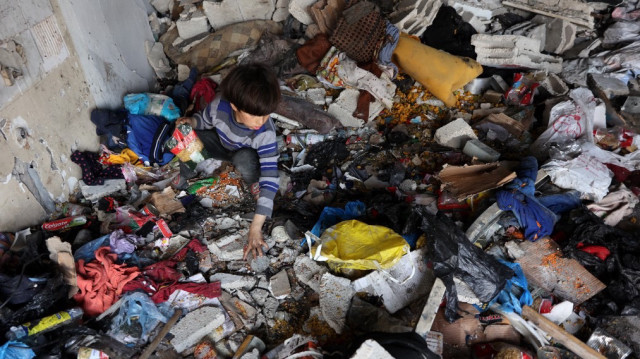 Un enfant tente de récupérer quelques objets au milieu de débris et d'objets éparpillés, dans une pièce d'un bâtiment de l'ONU abritant une clinique médicale où les Palestiniens déplacés se sont réfugiés, suite à une frappe israélienne, dans le nord de la bande de Gaza, le 2 avril 2025.