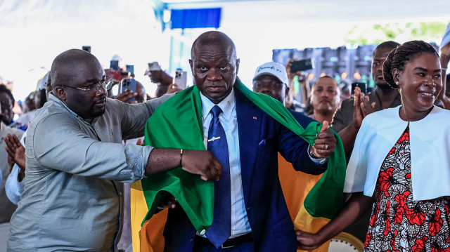 Le chef de la junte gabonaise, Brice Oligui Nguema (2e à droite), drapé d'un drapeau gabonais, aux côtés de son épouse Zita Nyangue Oligui Nguema (à droite), célébrant sa victoire à l'élection présidentielle, au siège de sa campagne électorale à Libreville, le 13 avril 2025. Le chef de la junte gabonaise, Brice Oligui Nguema, a remporté l'élection présidentielle avec 90,35 % des voix, selon les résultats provisoires publiés le 13 avril 2025 par le ministère de l'intérieur.