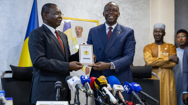 L'ancien ambassadeur du Tchad en Chine et le nouveau Premier ministre tchadien Allamaye Halina (à gauche) et le Premier ministre sortant Succes Masra (à droite) tiennent la constitution lors de la cérémonie de passation des pouvoirs dans les bureaux du Premier ministre à N'Djamena, le 24 mai 2024.