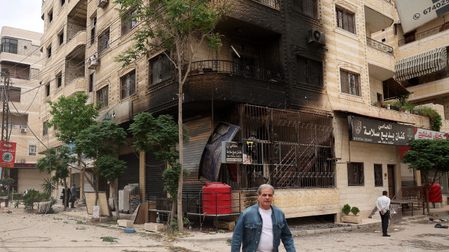 Un homme passe devant un bâtiment partiellement brûlé à la suite d'affrontements sectaires à Ashrafiyat Sahnaya, près de Damas, le 1er mai 2025. Le chef spirituel des Druzes syriens, le cheikh Hikmat al-Hijri, a condamné le 1er mai ce qu'il a qualifié de "campagne génocidaire" contre son peuple, après deux jours d'affrontements sectaires meurtriers.