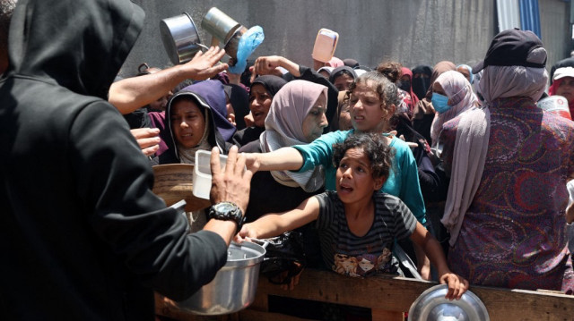 Des Palestiniens se bousculent pour obtenir un repas chaud, devant un point de distribution dans le camp de réfugiés de Nuseirat, dans le centre de la bande de Gaza, le 10 mai 2025.