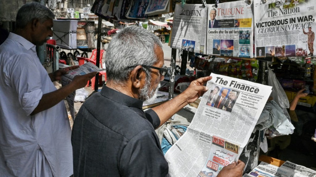 Des habitants lisent les journaux du matin à un kiosque de rue à Karachi, le 11 mai 2025.