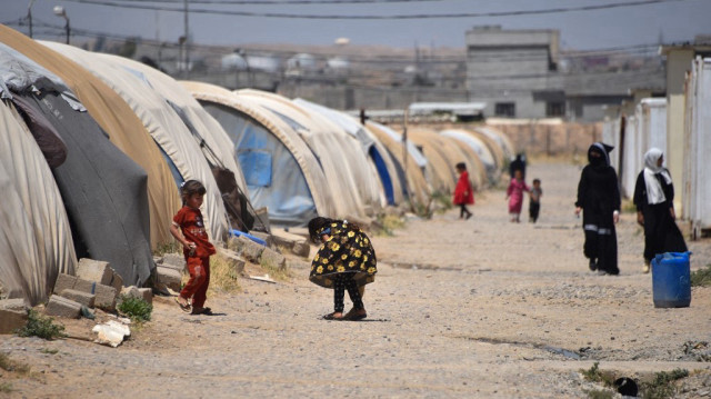 Des femmes et des enfants marchent dans le camp d'Al-Amal (anciennement Al-Jadaa), au sud de Mossoul, dans le nord de l'Irak, qui abrite des familles irakiennes rapatriées du camp syrien d'Al-Hol, le 8 mai 2025.