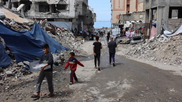 Des Palestiniens passent devant les débris des bâtiments détruits pendant la guerre entre Israël et le Hamas, dans la ville de Gaza, le 28 mars 2025.