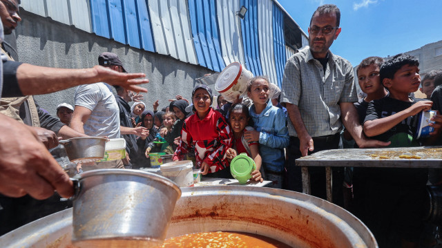 Des Palestiniens font la queue pour un repas chaud dans une cuisine caritative gérée par le Programme alimentaire mondial (PAM) des Nations unies dans le camp de réfugiés de Nuseirat, au centre de la bande de Gaza, le 26 avril 2025. L'agence alimentaire des Nations unies, l'un des principaux fournisseurs d'aide alimentaire dans le territoire palestinien assiégé, a déclaré le 25 avril qu'elle avait "livré ses derniers stocks de nourriture aux cuisines de repas chauds dans la bande de Gaza", où Israël bloque toute aide depuis plus de sept semaines, ajoutant que "ces cuisines devraient être complètement à court de nourriture dans les jours à venir".