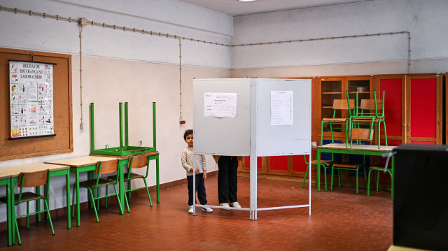 Un enfant regarde sous les deux bulletins de vote pendant que son père vote pour les élections générales au Portugal dans un bureau de vote à Lisbonne le 18 mai 2025. Les électeurs portugais se rendent aux urnes aujourd'hui dans le cadre d'une élection anticipée. Les électeurs portugais se sont rendus aux urnes le 18 mai pour les troisièmes élections générales du pays en trois ans. Le Premier ministre Luis Montenegro est donné gagnant, mais il n'a pas obtenu la majorité au parlement.