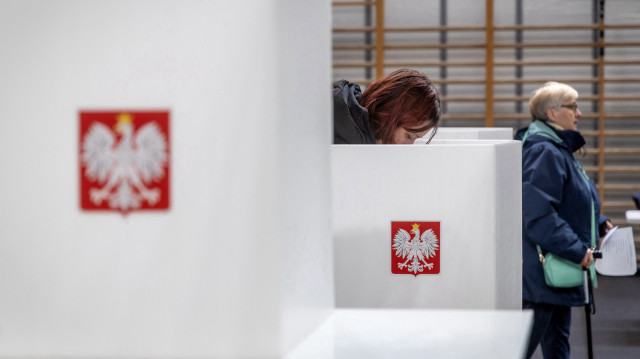 Un électeur se tient derrière un isoloir dans un bureau de vote à Varsovie, en Pologne, le 18 mai 2025, lors du premier tour des élections présidentielles. Les Polonais ont commencé à voter le 18 mai dans le cadre d'une élection présidentielle serrée qui sera décisive pour l'avenir du gouvernement centriste du pays.