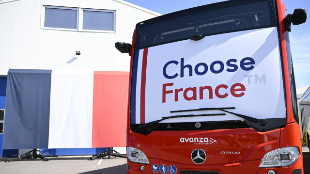Des autobus nouvellement fabriqués portant une bannière "Choose France" sont vus sur le parking de l'usine Evobus France à Ligny-en-Barrois, dans l'est de la France, le 19 mai 2025. Evobus est un constructeur allemand d'autobus et d'autocars, filiale du groupe allemand Daimler Truck.