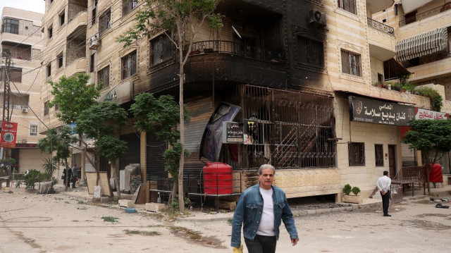 Un homme passe devant un bâtiment partiellement brûlé à la suite d'affrontements sectaires à Ashrafiyat Sahnaya, près de Damas, le 1er mai 2025. Le chef spirituel des Druzes syriens, le cheikh Hikmat al-Hijri, a condamné le 1er mai ce qu'il a appelé une ”campagne génocidaire” contre son peuple, après deux jours d'affrontements sectaires meurtriers.