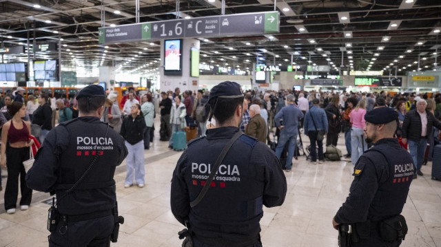 Des membres de la police régionale catalane, les Mossos d'Esquadra, patrouillent alors que des passagers attendent avant de monter dans leur train à la gare de Sants à Barcelone, le 29 avril 2025, au lendemain d'une panne d'électricité massive qui a touché l'ensemble de la péninsule ibérique et le sud de la France.