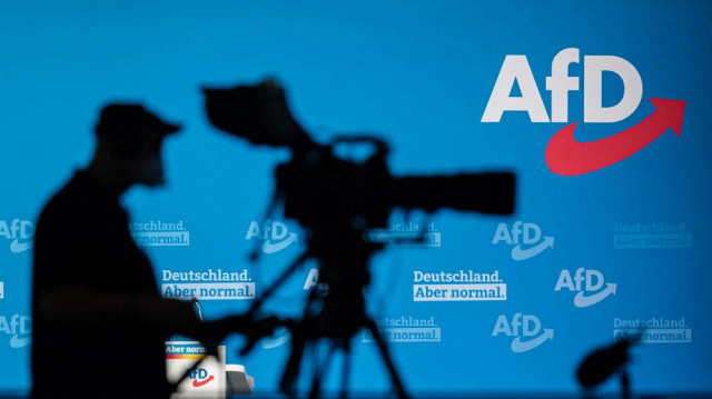 Un caméraman fait des silhouettes contre un mur avec le logo de l'AfD lors d'un congrès du parti d'extrême droite allemand Alternative pour l'Allemagne (AfD - Alternative fuer Deutschland) à Dresde, dans l'est de l'Allemagne, le 11 avril 2021.