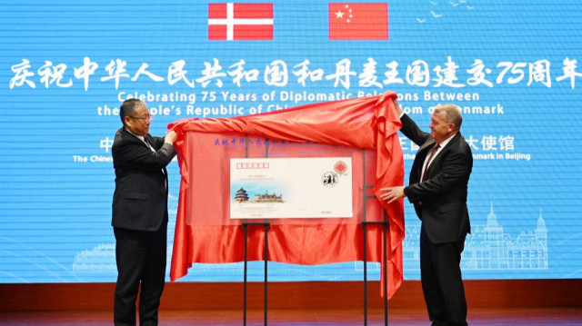 Le ministre danois des Affaires étrangères, Lars Lokke Rasmussen (à droite), dévoile une enveloppe commémorative avec Zheng Jianbang, vice-président du Comité permanent de l'Assemblée populaire nationale (à gauche), lors d'une réception marquant le 75e anniversaire des relations diplomatiques entre le Danemark et la Chine, à l'Association pour l'amitié avec les pays étrangers, à Pékin, le 19 mai 2025.