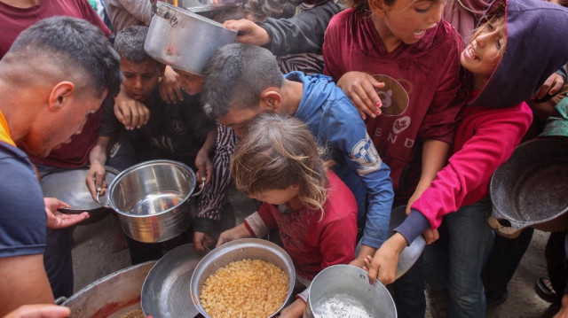 Des Palestiniens se bousculent pour obtenir une ration de nourriture chaude dans une cuisine de charité installée sur le campus de l'université islamique dans la ville de Gaza, le 12 mai 2025.