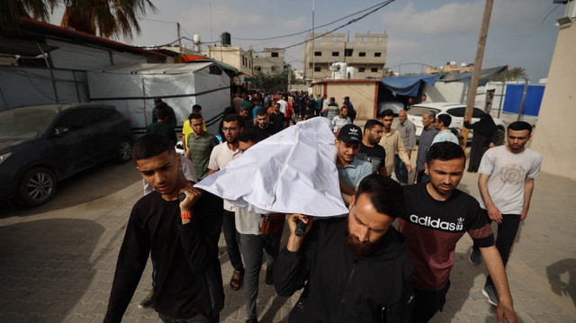 Des Palestiniens portent le corps d'une victime des frappes israéliennes à la morgue de l'hôpital des Martyrs d'Al-Aqsa à Deir el-Balah, dans le centre de la bande de Gaza, le 18 mai 2025.