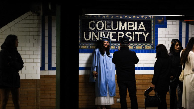 Un diplômé de l'université Columbia se fait photographier dans la station de métro lors de la cérémonie de remise des diplômes de l'université Columbia à New York, le 21 mai 2025.