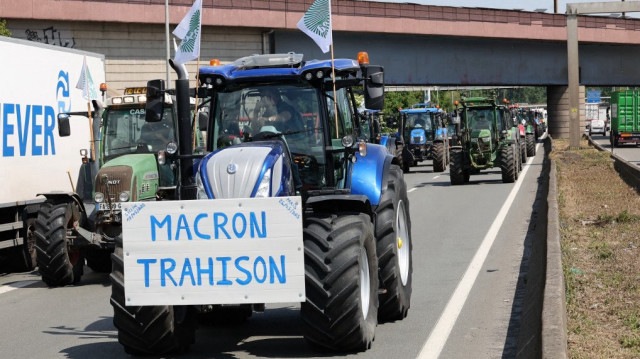 Des agriculteurs de la Fédération Nationale des Syndicats d'Exploitants Agricoles (FNSEA) bloquent l'autoroute A1 avec des tracteurs, portant un slogan "Macron, Trahison" près de Lille le 19 mai 2025, pour demander la levée des réglementations qui sont restrictives pour les agriculteurs.