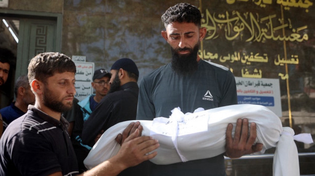 Un homme porte le corps enveloppé d'un enfant tué lors d'une frappe israélienne, à l'hôpital Al-Shifa dans la ville de Gaza le 26 mai 2025.