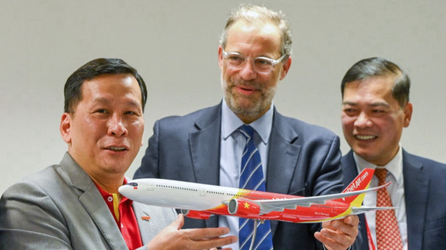 Benoit de Saint-Exupery (C), vice-président exécutif des ventes d'avions commerciaux d'Airbus, présente une maquette d'avion de ligne au PDG de Vietjet, Dinh Viet Phuong (G), après une cérémonie de signature au salon aéronautique de Singapour, le 22 février 2024.