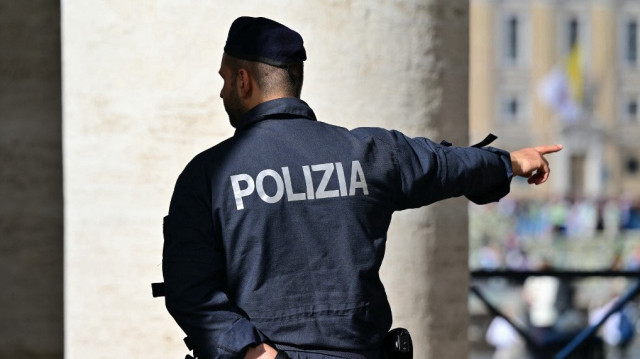 Un policier italien fait un geste à côté de la colonnade du Vatican, vue de Rome, un jour avant les funérailles du pape, le 25 avril 2025. 
