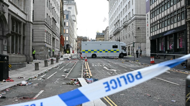 Des policiers se tiennent derrière un cordon de sécurité sur Water Street, à Liverpool, dans le nord-ouest de l’Angleterre, le 27 mai 2025, après qu’une voiture a foncé sur la foule rassemblée pour assister à la parade de la victoire en bus à impériale du Liverpool FC, célébrant son titre de Premier League.