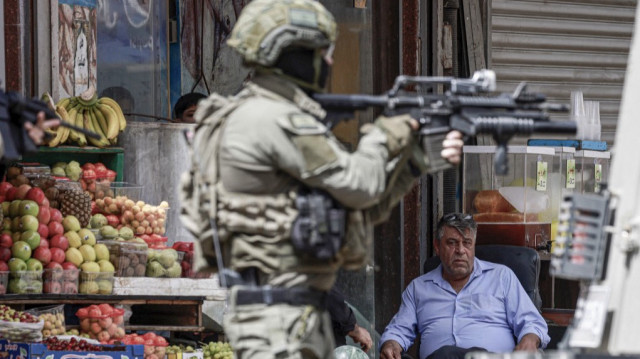 Un soldat de l'armée israélienne pointe son fusil sous le regard d'un Palestinien lors d'un raid au cœur de la ville palestinienne de Naplouse, en Palestine occupée, le 27 mai 2025.