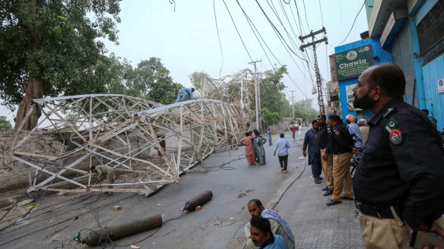 Des policiers pakistanais regardent des ouvriers enlever une tour de chemin de fer tombée après une tempête à Multan, le 28 mai 2025.