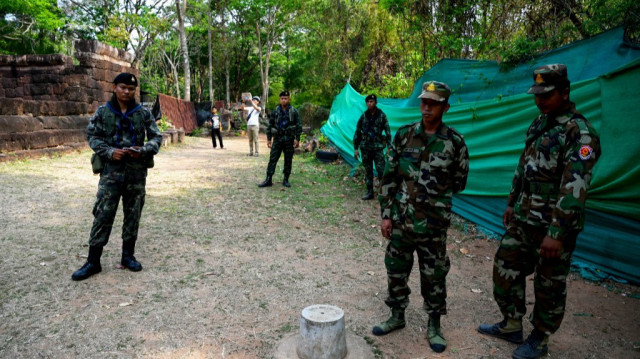 Des soldats cambodgiens (à droite) et thaïlandais (à gauche) montent la garde devant l'ancien temple khmer contesté Prasat Ta Muen Thom, ou Prasat Ta Moan Thom en khmer, à la frontière entre le Cambodge et la Thaïlande, dans la province d'Oddar Meanchey, le 26 mars 2025.