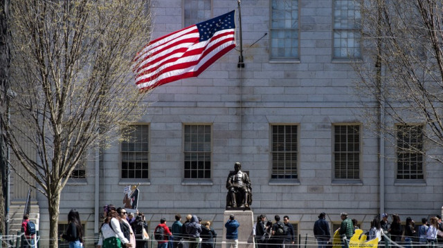 Des manifestants munis de pancartes se tiennent autour de la statue de John Harvard dans Harvard Yard après un rassemblement contre les attaques du président Donald Trump contre l'université de Harvard à l'université de Harvard à Cambridge, Massachusetts, le 17 avril 2025.