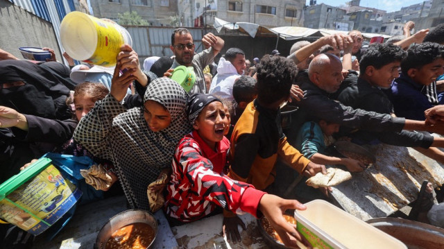 Des Palestiniens font la queue pour un repas chaud dans une cuisine de charité gérée par le Programme alimentaire mondial (PAM) des Nations unies dans le camp de réfugiés de Nuseirat, au centre de la bande de Gaza, le 26 avril 2025.