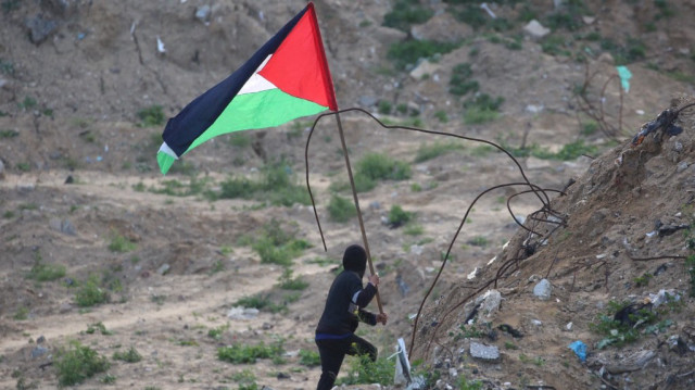 Un jeune Palestinien brandit le drapeau de la Palestine sur le site de la remise des corps de quatre otages israéliens à Khan Yunis, dans le sud de la bande de Gaza, le 20 février 2025.