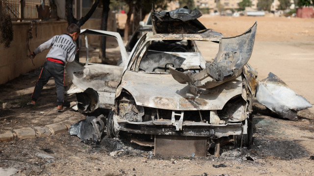 Un garçon vérifie un véhicule détruit à Ashrafiyat Sahnaya près de Damas le 1er mai 2025. Le chef spirituel des Druzes syriens, le cheikh Hikmat al-Hijri, a condamné le 1er mai ce qu'il a qualifié de "campagne génocidaire" contre son peuple, après deux jours d'affrontements sectaires meurtriers.