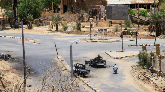 Des Soudanais passent à moto devant des véhicules militaires détruits, devant un hôpital de Khartoum, le 28 avril 2025. La guerre au Soudan a éclaté le 15 avril 2023 entre l'armée régulière, dirigée par Abdel Fattah al-Burhan, et les forces paramilitaires de soutien rapide (RSF), dirigées par son ancien adjoint Mohamed Hamdan Daglo.