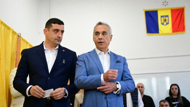 Le leader du parti souverain nationaliste "Alliance pour l'Union des Roumains" AUR George Simion (G) et l'ancien candidat Calin Georgescu posent pour les photographes après avoir déposé leurs bulletins de vote lors du premier tour de l'élection présidentielle à Mogosoaia, le 4 mai 2025.