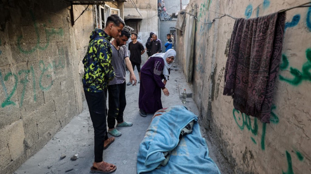 Des personnes se tiennent devant le corps enveloppé d'une personne tuée lors d'une frappe israélienne qui a touché un bâtiment dans le camp de réfugiés palestiniens de Bureij, dans le centre de la bande de Gaza, le 2 mai 2025.