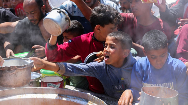 Des Palestiniens font la queue pour obtenir une portion de nourriture chaude dans une cuisine caritative du camp de réfugiés de Nuseirat, dans le centre de la bande de Gaza, le 5 mai 2025.