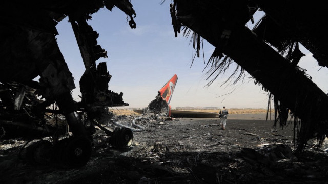 Un houthi marche à côté d'un avion détruit à l'aéroport international de Sanaa, le 7 mai 2025.