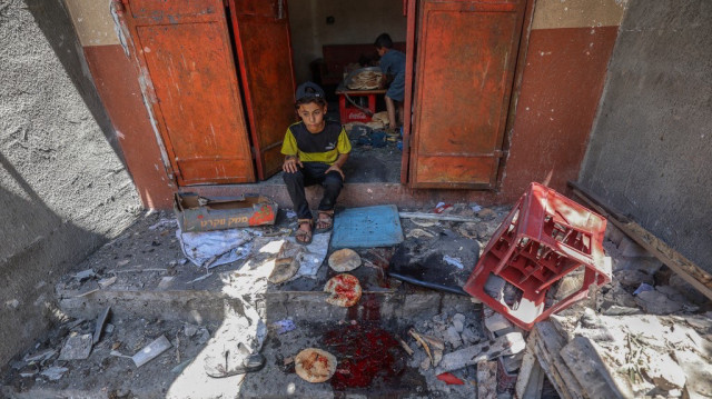 Des garçons palestiniens récupèrent du pain dans une boulangerie de fortune touchée par les frappes israéliennes dans le camp de réfugiés de Nuseirat, au centre de la bande de Gaza, le 8 mai 2025.