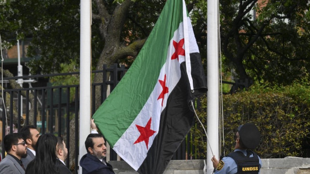 Le ministre syrien des Affaires étrangères, Asaad al-Shaibani, brandit le nouveau drapeau syrien lors d'une cérémonie au siège des Nations Unies à New York, le 25 avril 2025.