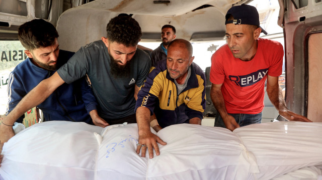 Des personnes déchargent les corps enveloppés des personnes tuées lors d'une frappe israélienne, à l'hôpital Al-Shifa dans la ville de Gaza, le 26 mai 2025. Les sauveteurs ont déclaré qu'au moins 20 personnes ont été tuées, principalement des enfants, et plus de 60 blessées lors d'une frappe israélienne sur une école abritant des personnes déplacées dans la ville de Gaza le 26 mai.