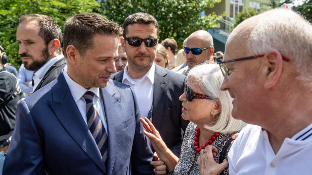 Le maire de Varsovie et membre du parti centriste au pouvoir, la Coalition civique, Rafal Trzaskowski (G), discute avec des électeurs à la sortie d'un bureau de vote à Varsovie, en Pologne, lors du second tour des élections présidentielles, le 1er juin 2025. Les bureaux de vote ont ouvert pour un second tour serré de l'élection présidentielle qui aura des implications majeures pour le rôle du pays en Europe. Les sondages d'opinion ont prédit une course extrêmement serrée entre l'historien nationaliste Karol Nawrocki et le maire pro-UE de Varsovie Rafal Trzaskowski, au coude à coude avant le vote.