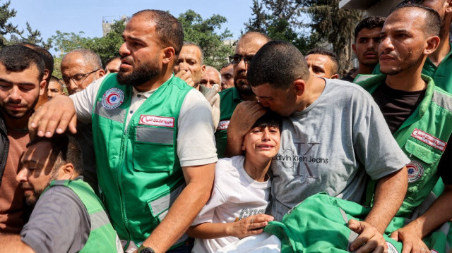 Un homme réconforte un garçon en deuil près du corps d'un des trois ambulanciers tués la veille par un bombardement israélien sur le quartier de Tuffah, lors des funérailles à la clinique Sheikh Radwan dans le quartier Sheikh Radwan de la ville de Gaza, le 10 juin 2025.