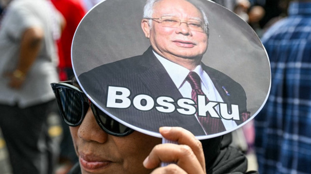 Une femme tient un éventail portant une photo de l'ancien premier ministre malaisien Najib Razak et l'inscription "Mon patron", alors que des sympathisants se rassemblent pour son audience en appel devant le palais de justice, qui abrite la cour d'appel et la cour fédérale de Malaisie, à Putrajaya, le 6 janvier 2025.