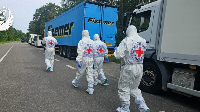 Cette photo prise et diffusée par le Quartier général de coordination pour le traitement des prisonniers de guerre le 11 juin 2025 montre des représentants de la Croix-Rouge internationale passant devant le cortège de réfrigérateurs du convoi transportant les corps des soldats ukrainiens, dans le contexte de l'invasion de l'Ukraine par la Russie.