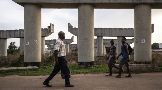 Des piétons marchent à côté d'un pont en construction dans le quartier central des affaires d'Abuja, le 22 mai 2025.