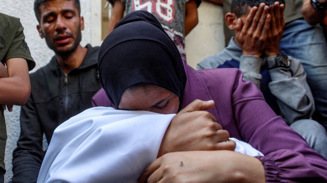 Une femme pleure le corps d'une victime qui a été tuée lors d'un bombardement israélien pendant la nuit alors qu'elle est assise avec d'autres personnes en deuil à l'hôpital Al-Shifa dans la ville de Gaza le 4 juin 2025.