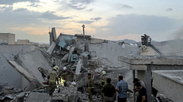 Des personnes et des secouristes se rassemblent au sommet d'un bâtiment touché par une frappe israélienne à Téhéran le 13 juin 2025.