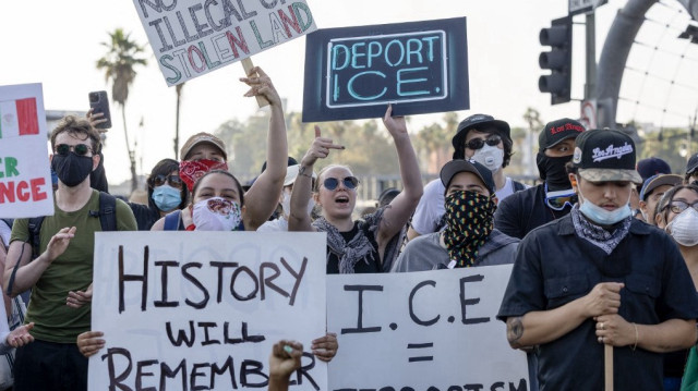 Des personnes tiennent des pancartes alors que des manifestants affrontent les forces de l'ordre dans les rues entourant le bâtiment fédéral lors d'une manifestation à la suite des opérations fédérales d'immigration à Los Angeles, en Californie, le 8 juin 2025.