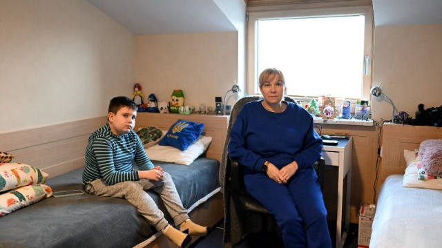Les réfugiés ukrainiens Natalia Kapustina et son fils de 8 ans Kostya posent pour une photo alors qu'ils sont assis dans leur chambre dans un centre de réfugiés à Borzecin Duzy, dans la région de Masovie, le 6 février 2025.