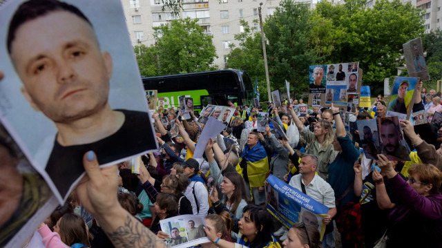 Des parents et des amis tiennent des photos de leurs proches lors d'un échange de prisonniers de guerre dans un lieu tenu secret en Ukraine, le 12 juin 2025, dans le contexte de l'invasion russe de l'Ukraine. L'Ukraine et la Russie ont déclaré le 12 juin 2025 qu'elles avaient échangé un nouveau groupe de prisonniers de guerre, le troisième échange cette semaine dans le cadre d'un accord conclu lors de pourparlers de paix en Türkiye la semaine précédente.