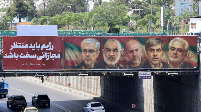Une affiche montrant les portraits de généraux militaires et de scientifiques nucléaires iraniens, tués lors de l'attaque israélienne du 13 juin, est accrochée sur un pont à Téhéran le 14 juin 2025. L'armée israélienne a déclaré que ses avions de combat étaient prêts à reprendre leurs frappes sur des cibles à Téhéran, après avoir annoncé qu'ils avaient touché des défenses aériennes dans la capitale iranienne au cours de la nuit, alors qu'Israël et l'Iran échangent des tirs avec une telle intensité pour la première fois après des décennies d'inimitié et de conflit par procuration, et que l'on craint qu'un conflit prolongé n'engloutisse la région.